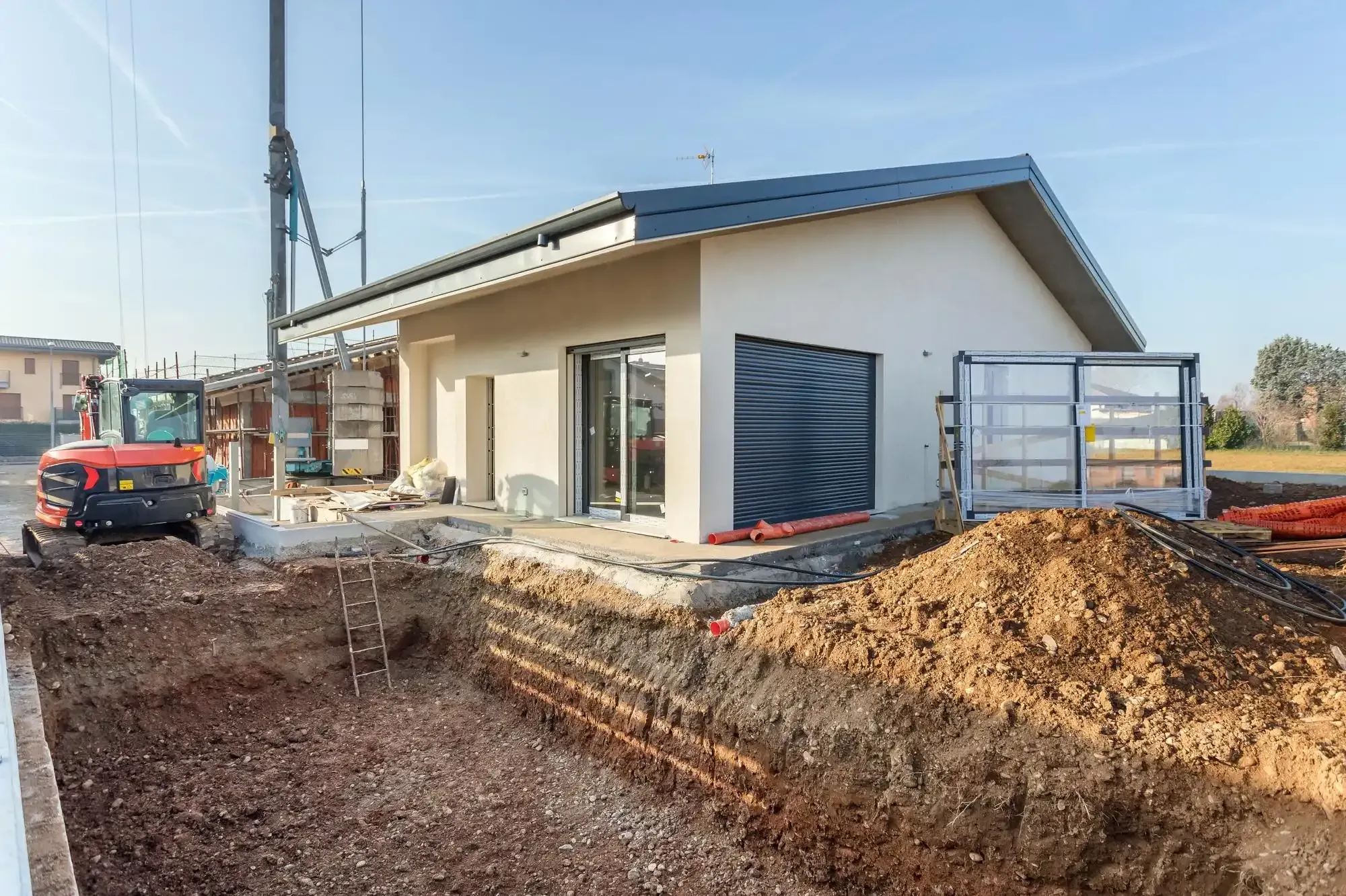 New single-story home under construction with excavated trenches for underground utility lines.