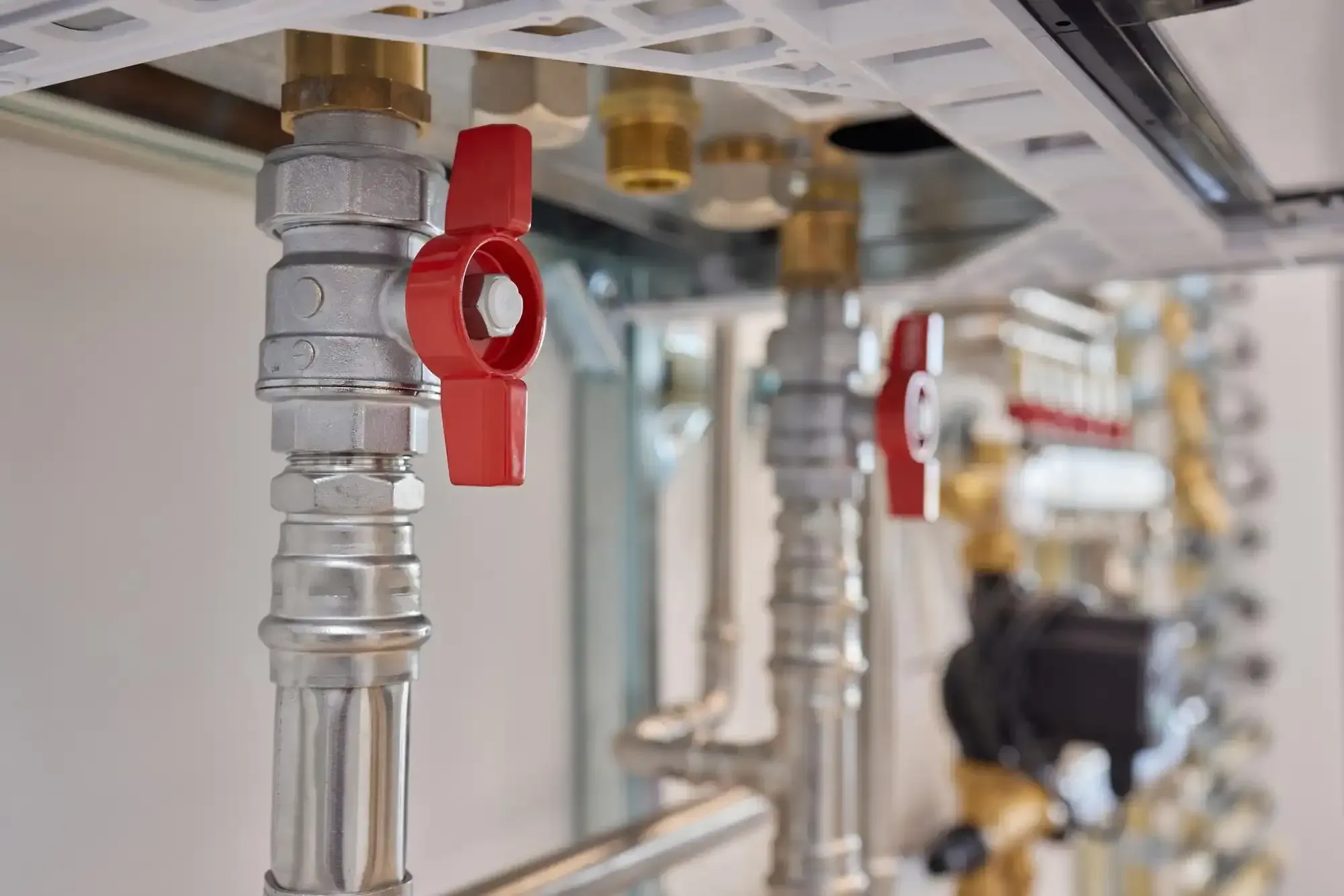 Water supply lines with red-handle shutoff valves, used to isolate a line during slab leak repair.